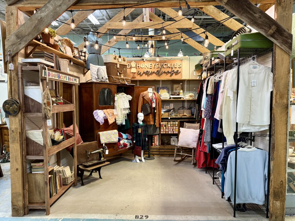 Wild Honeysuckle Mercantile vintage booth featuring antique furniture, clothing racks, and rustic wood display.